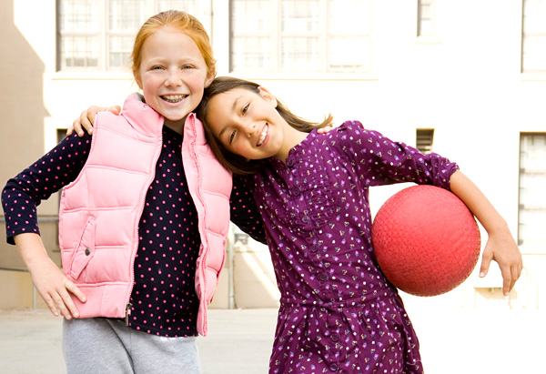 image of two young girls, one holding a ball