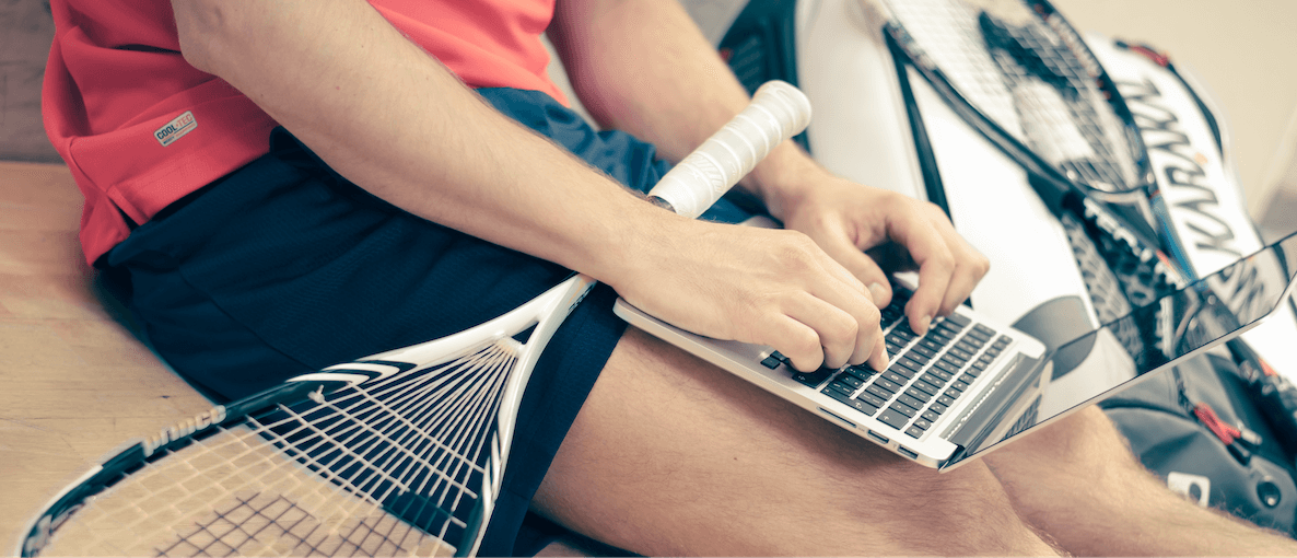 A picture of a man with a squash racket and a computer