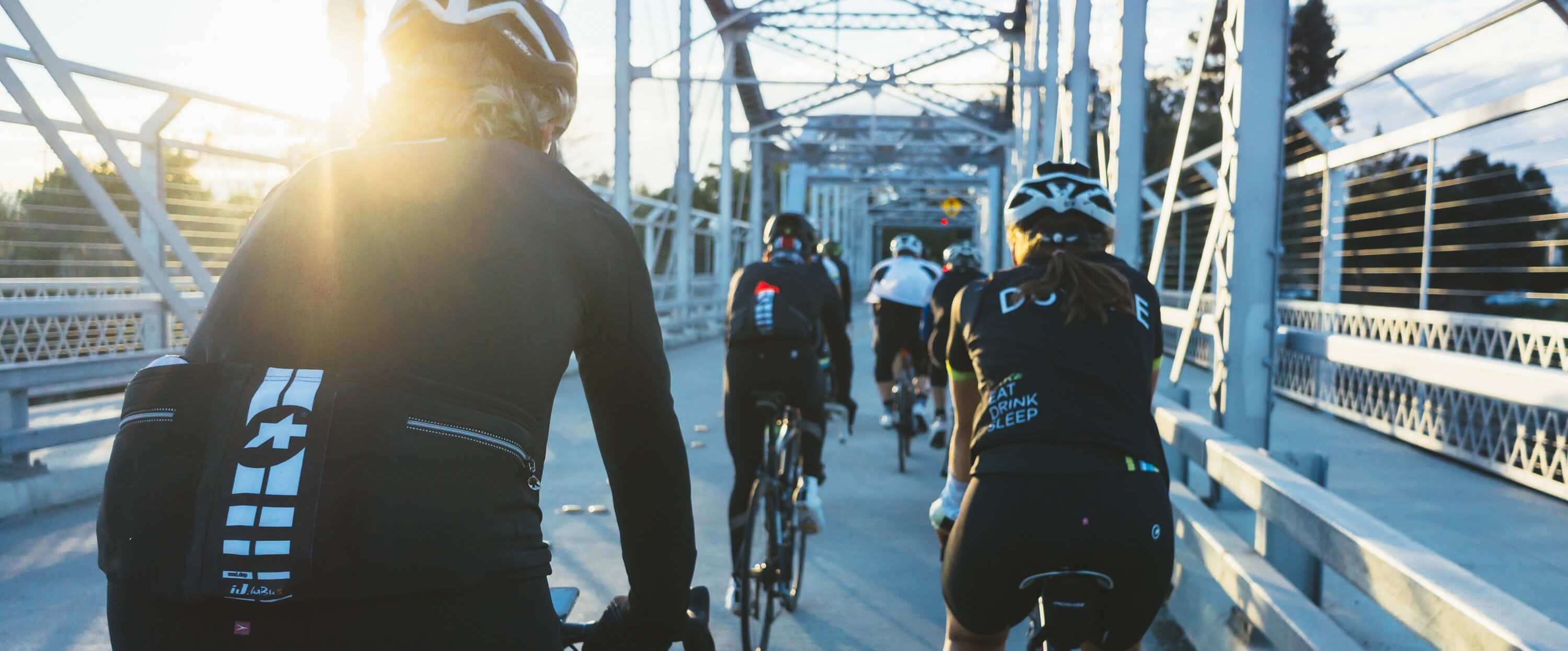 A group of bikers on a bridge early in the morning