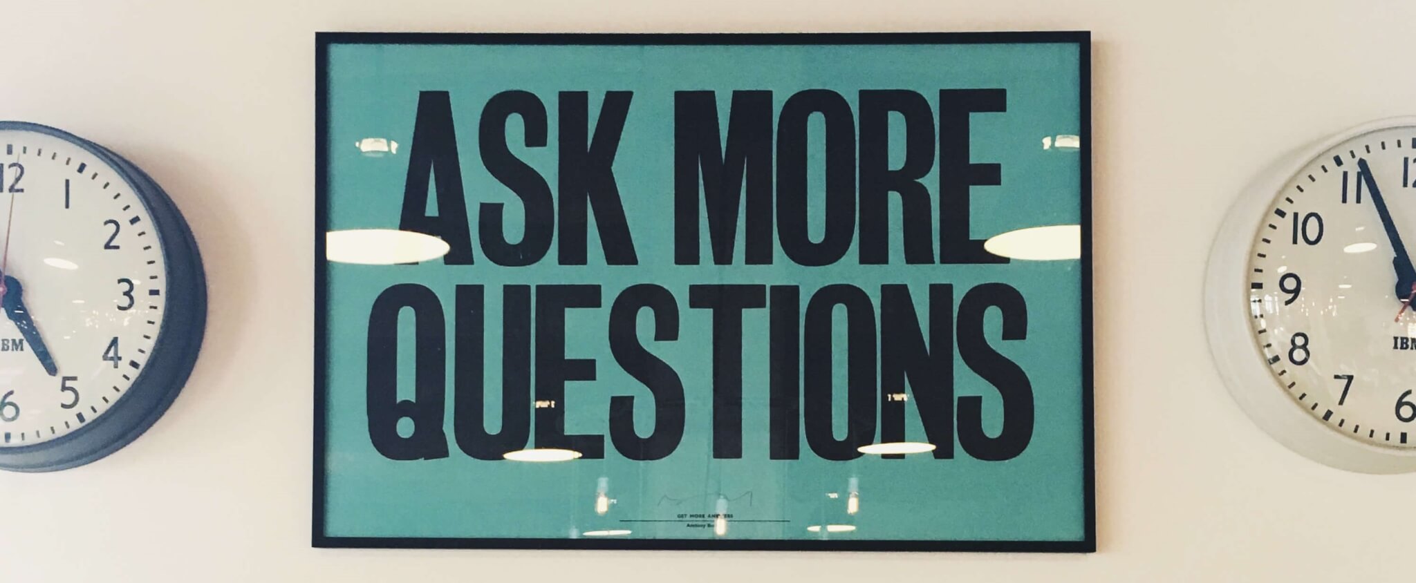 A bright sign that says "ask more questions" in bold letters
