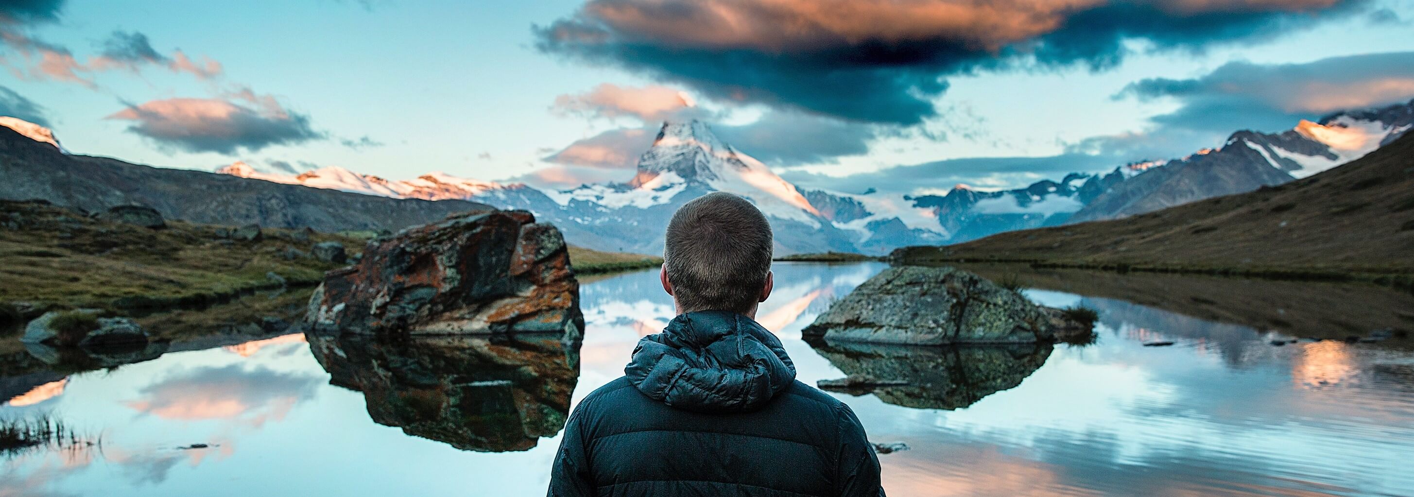 A young man somberly looking out at a river with a view